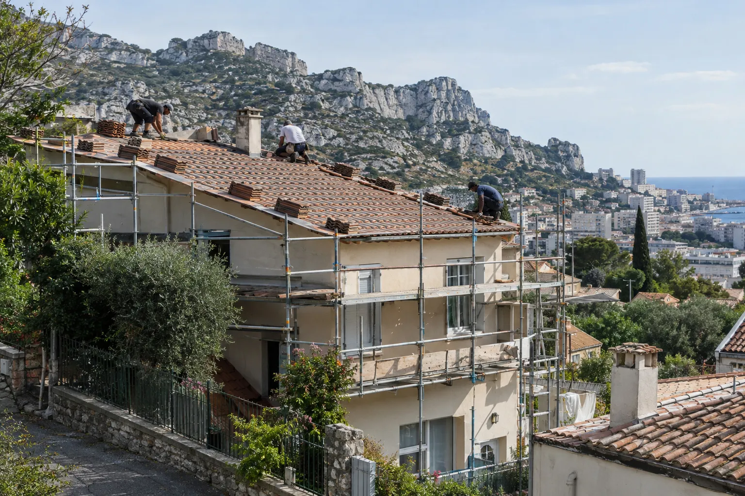 Couvreurs sur le toit d'une villa en pente, échafaudage en façade, collines calcaires et mer au loin dans l'est de Marseille